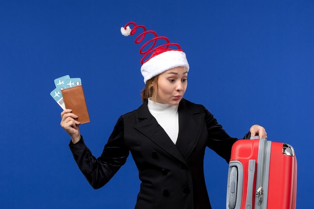 Vorderansicht junge Frau, die Tickets mit Tasche auf blauem Hintergrundfeiertagsflugzeugurlaub hält