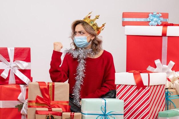 Vorderansicht junge Frau, die um Weihnachtsgeschenke in der Maske wütend sitzt