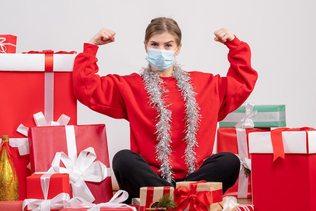 Vorderansicht junge Frau, die um Weihnachtsgeschenke in der sterilen Maske sitzt