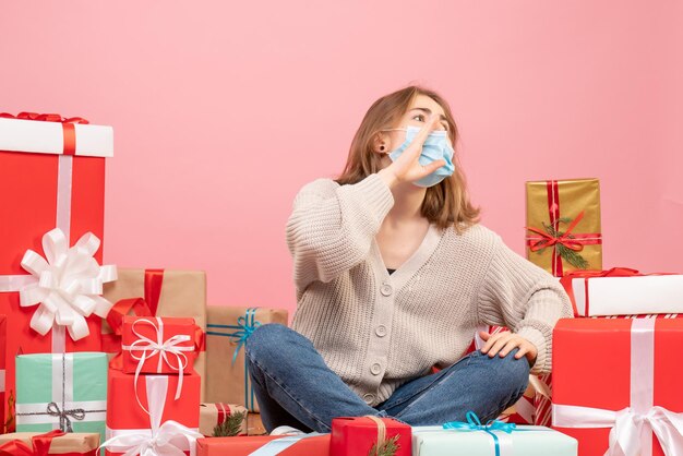 Vorderansicht junge Frau, die um Weihnachtsgeschenke in der sterilen Maske sitzt