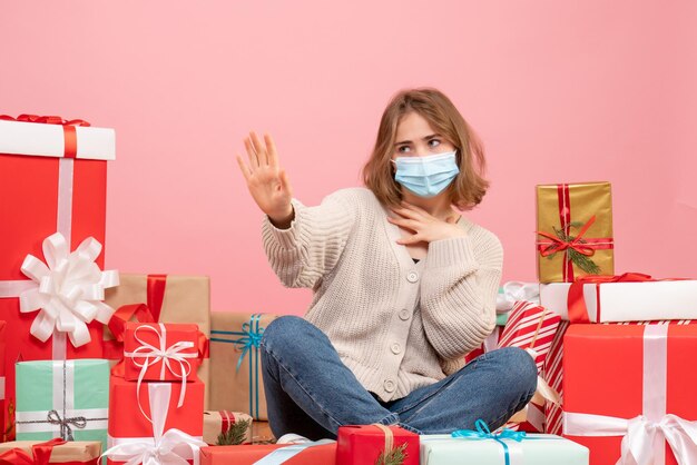 Vorderansicht junge Frau, die um Weihnachtsgeschenke in der sterilen Maske sitzt