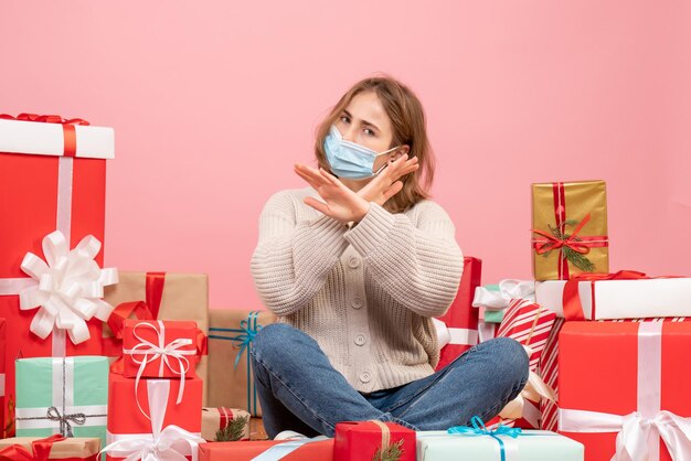 Vorderansicht junge Frau, die um Weihnachtsgeschenke in der sterilen Maske sitzt