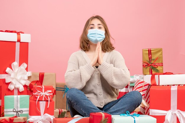 Vorderansicht junge Frau, die um Weihnachtsgeschenke in der sterilen Maske sitzt