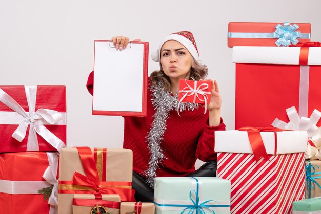 Vorderansicht junge Frau, die um Weihnachtsgeschenke mit Hinweis sitzt