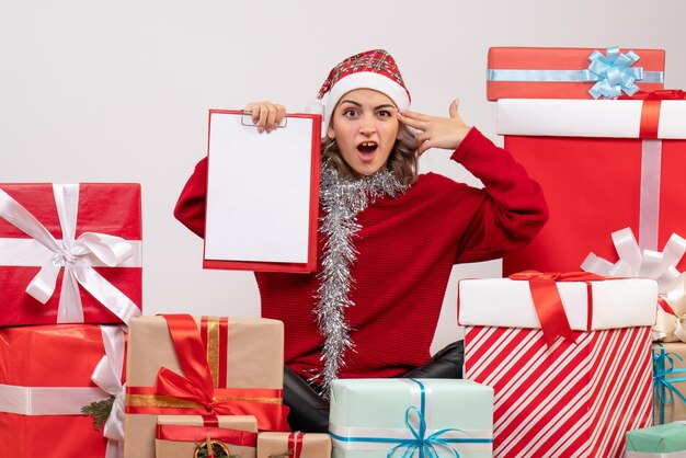 Vorderansicht junge Frau, die um Weihnachtsgeschenke mit Hinweis sitzt