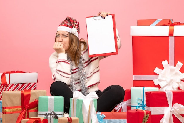 Vorderansicht junge Frau, die um Weihnachtsgeschenke sitzt mit Dateinotiz sitzt