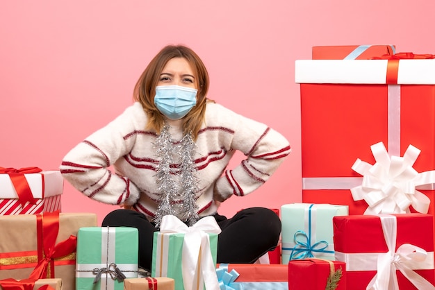 Kostenloses Foto vorderansicht junge frau, die um weihnachtsgeschenke sitzt