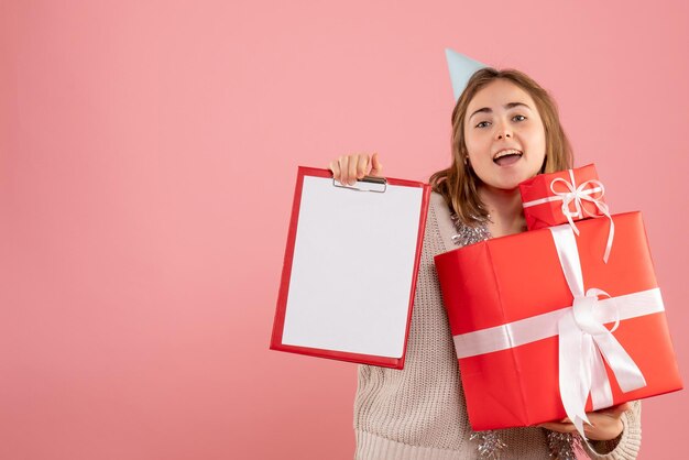 Vorderansicht junge Frau, die Weihnachtsgeschenke und Notiz hält