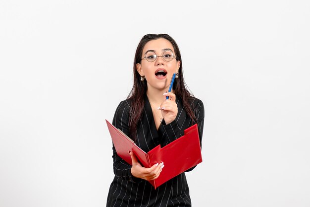 Vorderansicht junge Frau im dunklen strengen Anzug hält rote Datei auf weißem Hintergrund Büro Business Job Mode weibliche Dokumente