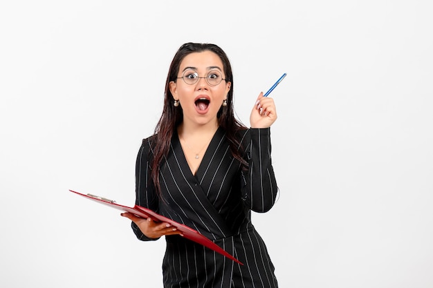 Vorderansicht junge Frau im dunklen strengen Anzug hält rote Datei auf weißem Hintergrund Büro Business Job Mode weibliches Dokument
