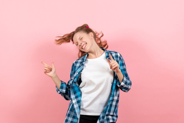 Vorderansicht junge Frau im karierten Hemd, das auf rosa Hintergrundjugendmodellemotionsfrauenkindmädchen aufwirft und tanzt