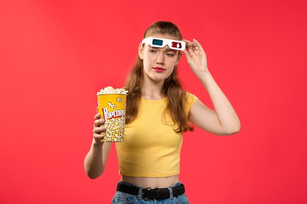Vorderansicht junge Frau im Kino, die Popcorn auf der roten Wand Filmtheaterkino weibliche Farbe hält