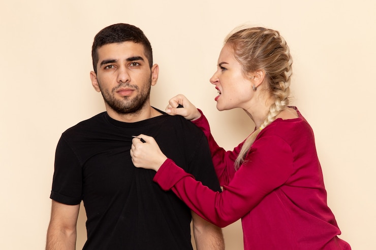 Kostenlose Foto vorderansicht junge frau im roten hemd, das mit mann auf dem cremeraumfoto emotion häusliche gewalt streitet