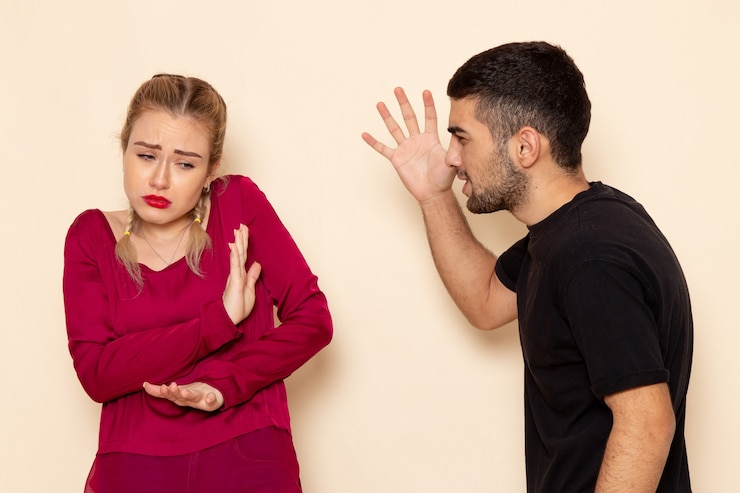 Kostenlose Foto vorderansicht junge frau im roten hemd leidet unter physischen bedrohungen und gewalt auf dem cremeboden weibliches stofffoto