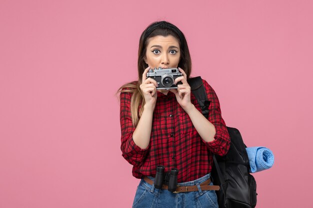 Vorderansicht junge Frau im roten Hemd mit Kamera auf der rosa Hintergrundmodellfotofrau