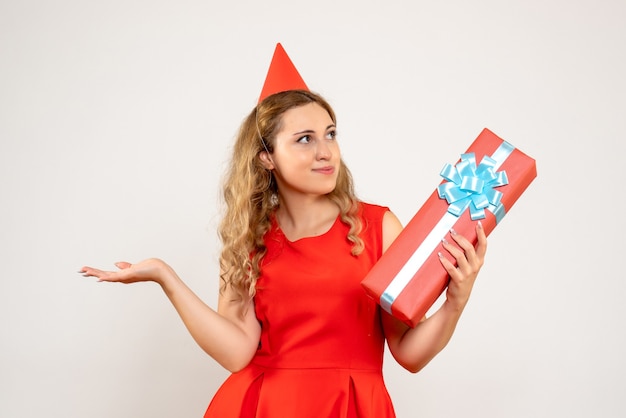 Vorderansicht junge Frau im roten Kleid, das Weihnachten mit Geschenk feiert