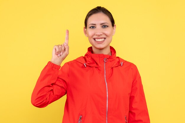 Vorderansicht junge Frau im roten Mantel auf gelbem Hintergrund