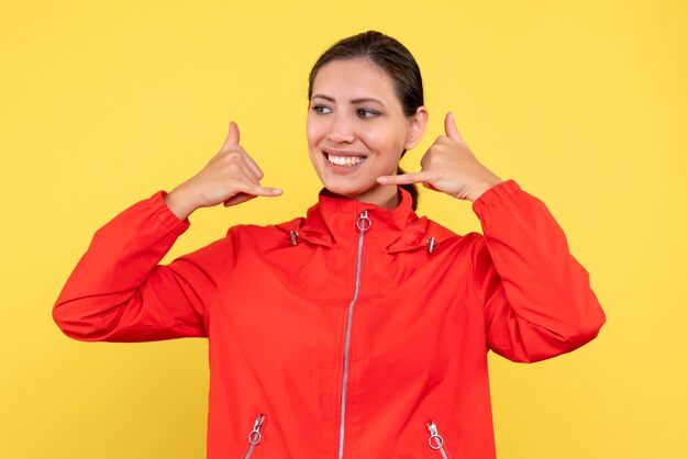 Vorderansicht junge Frau im roten Mantel auf gelbem Hintergrund