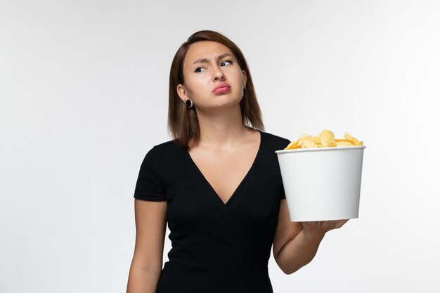 Vorderansicht junge Frau im schwarzen Hemd, das Kartoffelchips auf weißer Oberfläche hält