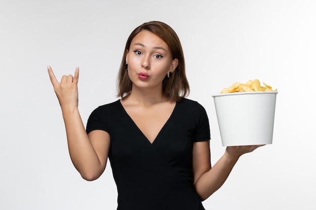 Vorderansicht junge Frau im schwarzen Hemd, das Kartoffelchips auf weißer Oberfläche hält
