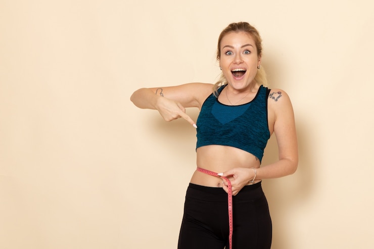 Kostenlose Foto vorderansicht junge frau im sportoutfit, das ihre größen und taille misst