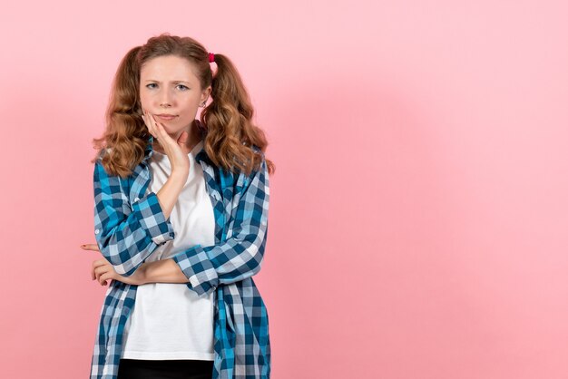 Vorderansicht junge Frau in blau kariertem Hemd, das auf dem rosa Hintergrundemotionsmädchenmodefarbmodelljugendkind aufwirft