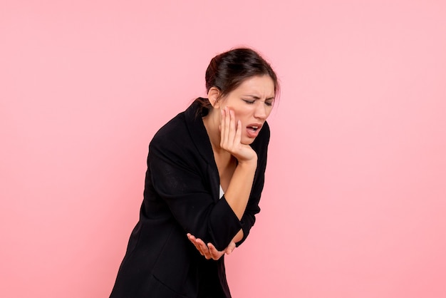 Vorderansicht junge Frau in der dunklen Jacke, die unter Zahnschmerzen auf rosa Hintergrund leidet