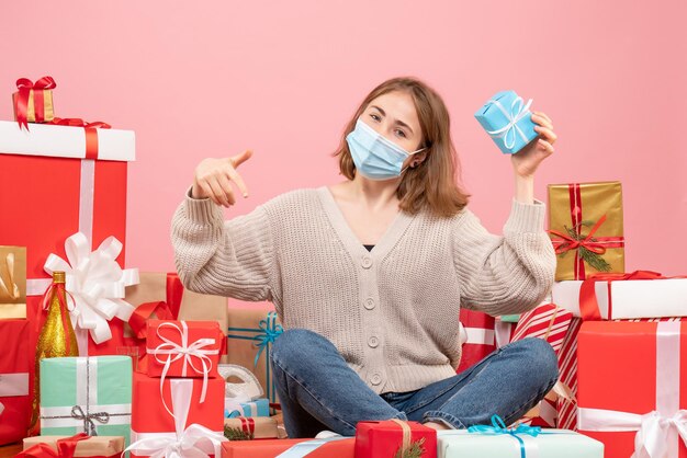 Vorderansicht junge Frau in der Maske, die um Weihnachtsgeschenke sitzt