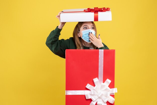 Vorderansicht junge Frau in Geschenkbox in steriler Maske