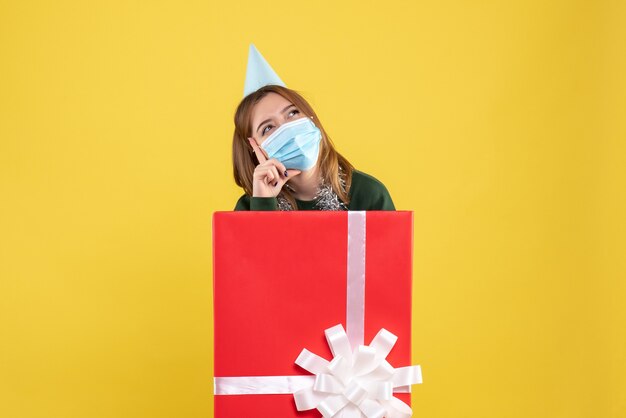 Vorderansicht junge Frau in Geschenkbox in steriler Maske