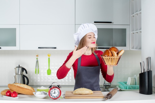 Vorderansicht junge Frau in Kochmütze und Schürze riechendes Laib in der Küche