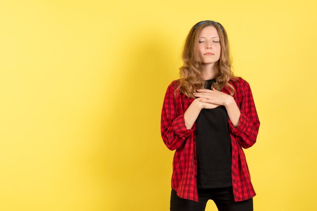 Vorderansicht junge Frau in rotem kariertem Hemd, das auf dem gelben Hintergrund menschliches Mädchen-Emotionsfarbmodellfrau aufwirft