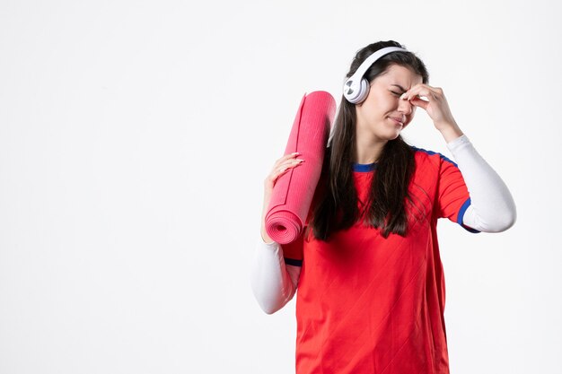 Vorderansicht junge Frau in Sportkleidung, die Yogamatte hält