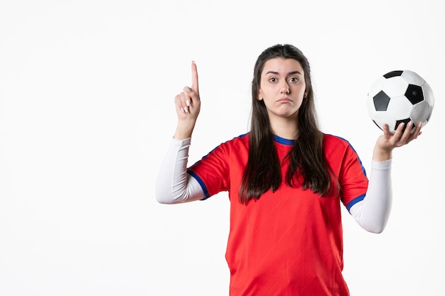Vorderansicht junge Frau in Sportkleidung mit Fußball auf weißer Wand