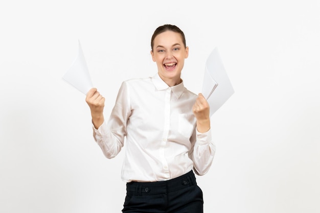 Vorderansicht junge Frau in weißer Bluse, die Dokumente hält, die sich auf weißem Hintergrund freuen, weibliche Jobgefühle, die Büro fühlen