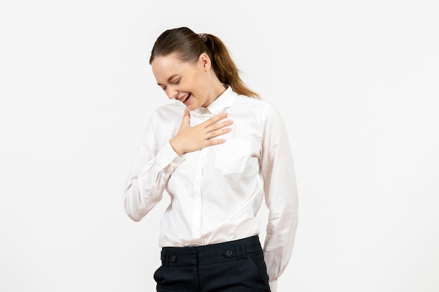 Vorderansicht junge Frau in weißer Bluse lachend auf weißem Hintergrund weibliches Job-Büro-Emotion-Gefühl-Modell