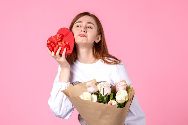 Vorderansicht junge Frau mit Blumen und Geschenk als Frauentag Geschenk auf rosa Hintergrund horizontalen März Gleichheit Datum Rose Frau Liebe sinnlich