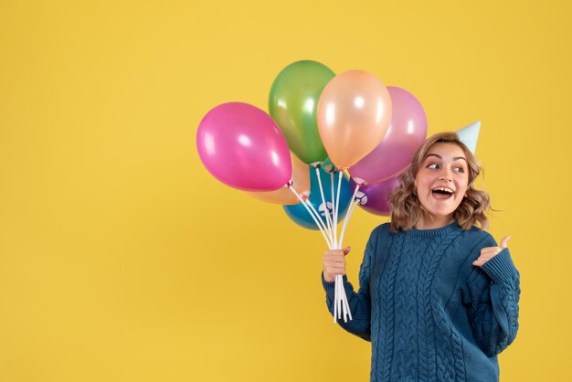 Vorderansicht junge Frau mit bunten Luftballons