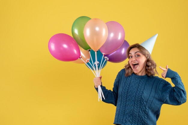 Vorderansicht junge Frau mit bunten Luftballons