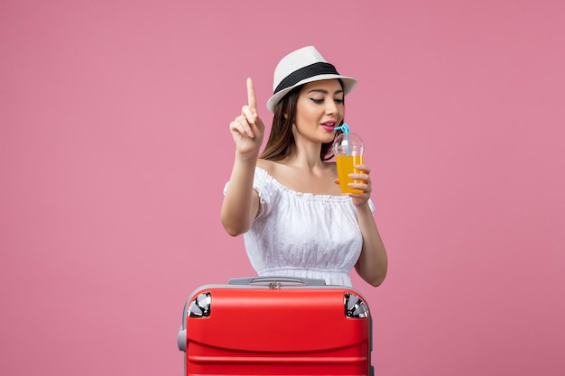 Vorderansicht junge Frau mit Cocktail im Sommerurlaub auf hellrosa Wand Urlaub Hitze Reise Sommerreise