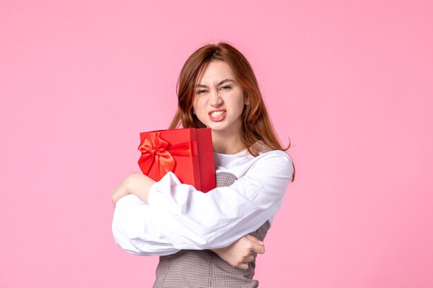 Vorderansicht junge Frau mit Geschenk im roten Paket auf rosa Hintergrund Datum März horizontale Liebe Frau Gleichheit