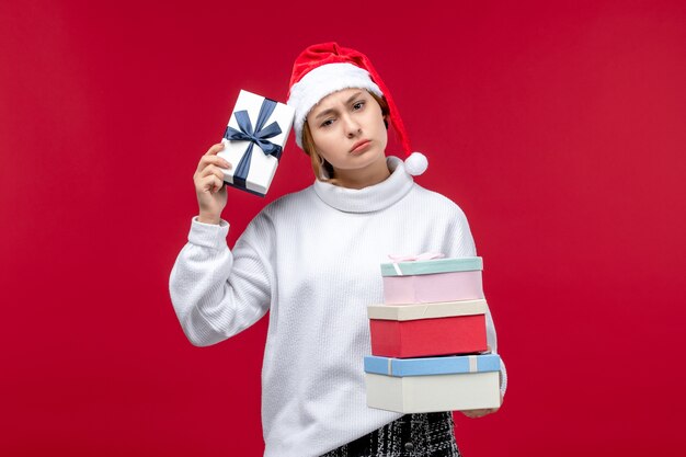 Vorderansicht junge Frau mit Neujahrsgeschenken auf rotem Schreibtisch