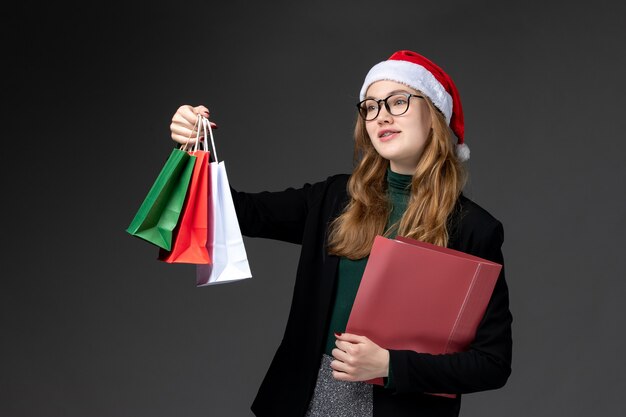 Vorderansicht junge Frau mit Paketen auf der dunklen Wand Geschenk Neujahr Weihnachten