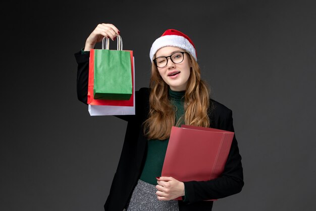 Kostenloses Foto vorderansicht junge frau mit paketen auf dunklem boden geschenk neujahr weihnachten