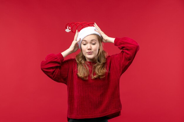 Vorderansicht junge Frau mit rotem Weihnachtsmütze auf rotem Schreibtisch Urlaub Weihnachten
