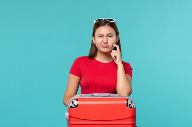 Vorderansicht junge Frau mit roter Tasche, die für Urlaub auf dem blauen Raum bereit macht