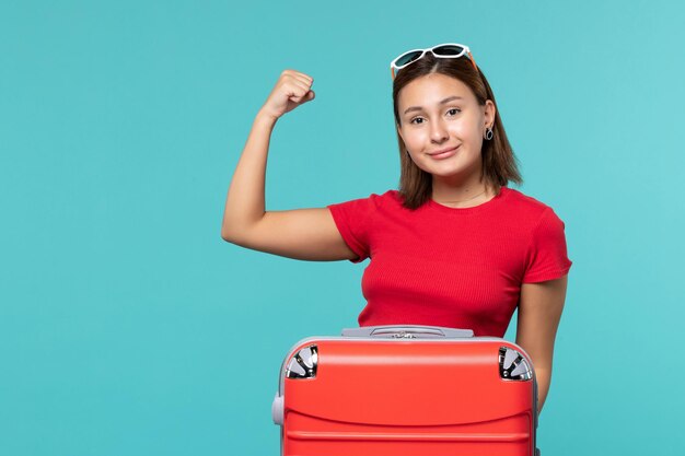 Vorderansicht junge Frau mit roter Tasche, die für Urlaub auf dem blauen Raum vorbereitet