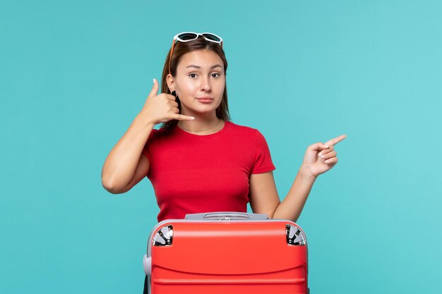 Vorderansicht junge Frau mit roter Tasche, die für Urlaub auf dem blauen Raum vorbereitet