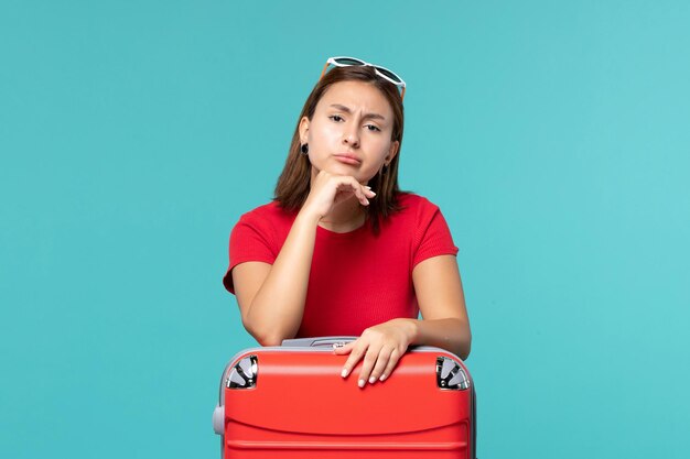 Vorderansicht junge Frau mit roter Tasche, die für Urlaub auf dem blauen Raum vorbereitet