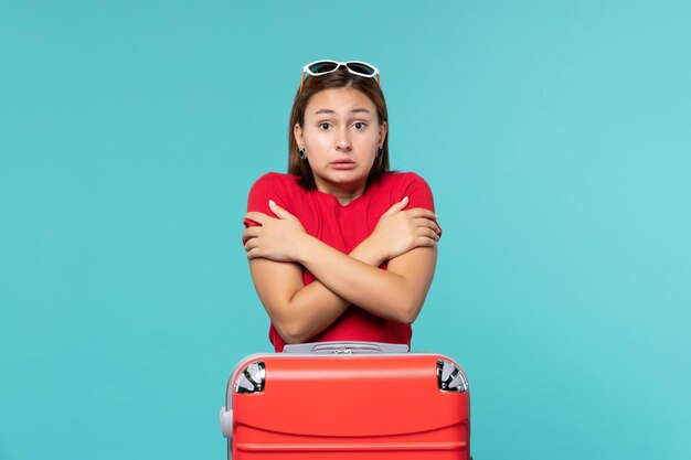 Vorderansicht junge Frau mit roter Tasche, die für Urlaub auf dem blauen Raum vorbereitet